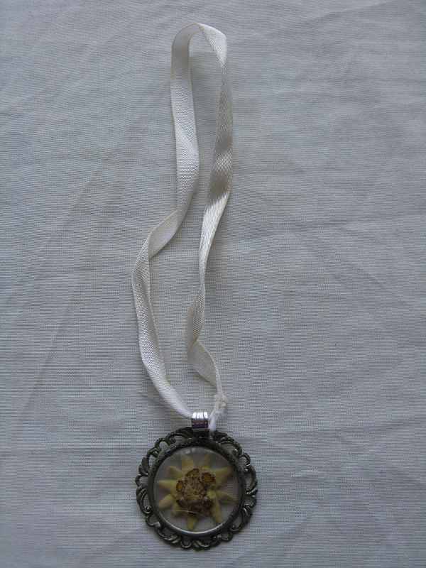 RIBBON NECKLACE WITH POSSIBLY FLOWER IN INNER OF PENDANT. D 3.2cm
