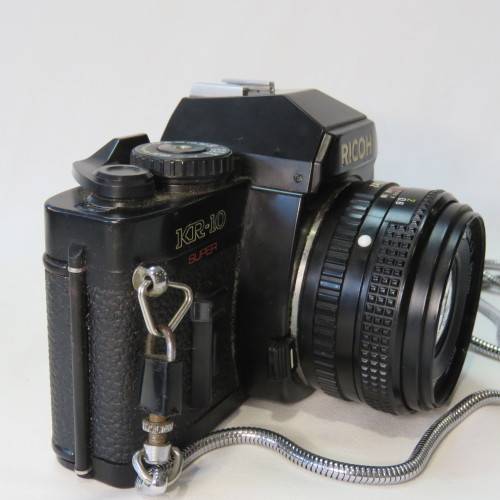 Ricoh KR-10 camera in pouch with Rikenon 1:2 50 mm lens and booklets