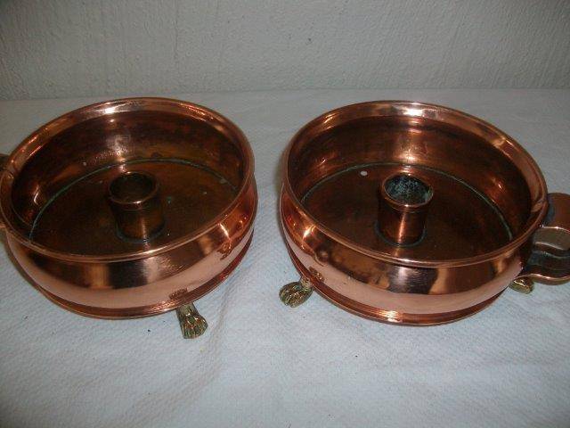 A pair of copper with brass feet candle holders