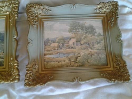 A pair of small pretty hard plastic ornate frames with painted home scenes
