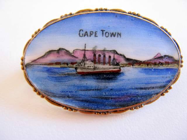 A PLATED AND ENAMEL BROOCH WITH A SCENE OF TABLE MOUNTAIN.