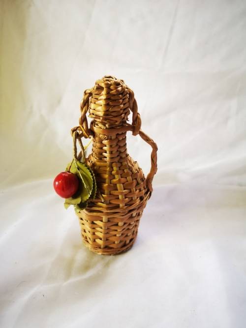 A small bottle of liquor in a beautiful woven basket - still sealed