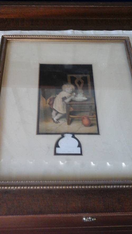 CUTE PICTURE OF A VICTORIAN CHILD IN A KITCHEN EATING BREAKFAST.