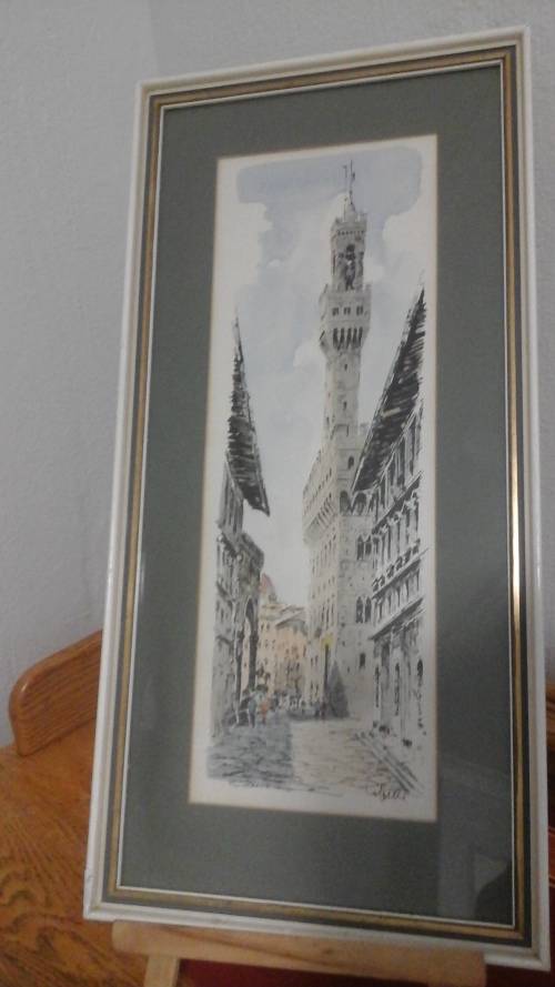 A MAJESTIC SIGNED PRINT OF BUILDINGS IN A WHITE SHABBY SHICK FRAME WITH A GREEN AND GOLD BORDER.