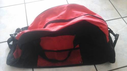 A HANDY RED LIGHTWEIGHT TRAVEL BAG. HAS HANDLES AND A STRAP