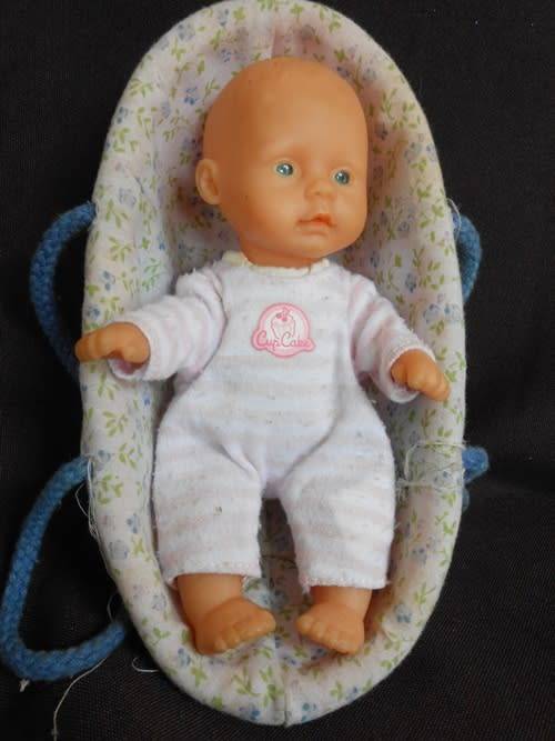 small soft bodied Simba doll in plastic carry basket