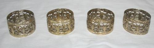 A COLLECTION OF FOUR GOLD COLOR METAL SERVIETTE RINGS