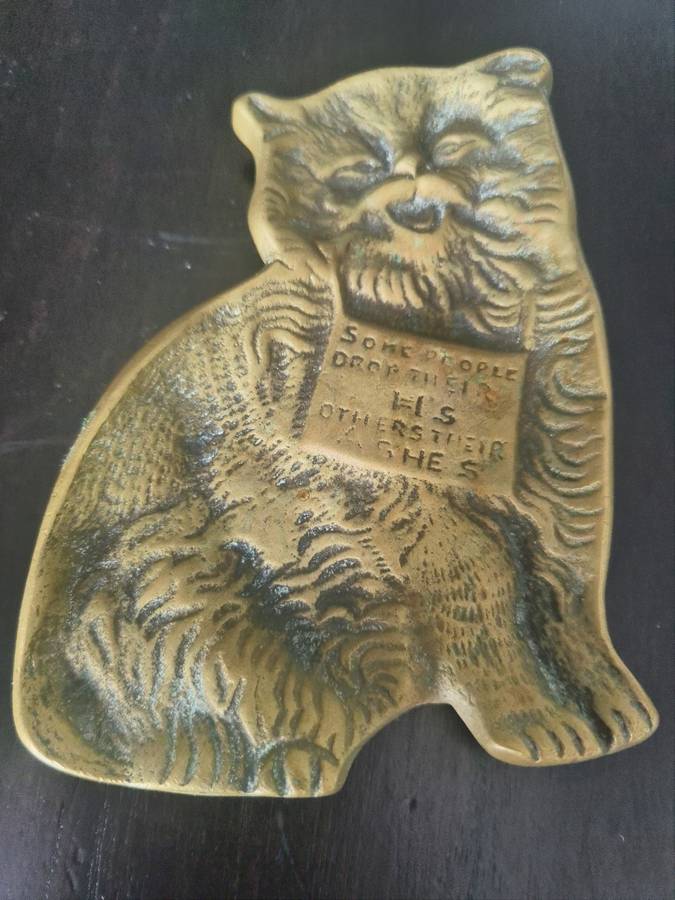 A lovely vintage brass flat cat ashtray with and embellished sign `Some people drop their H`s others