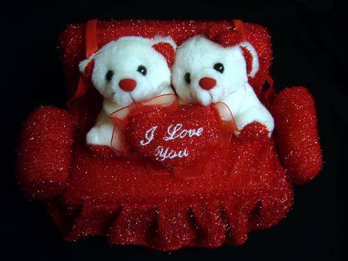 TWO LOVE BEARS SITTING ON A RED COUCH HOLDING A RED HEART