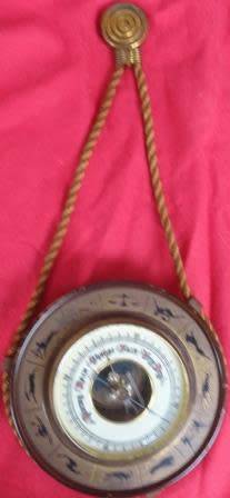 A barometer with signs of the zodiac as a surround and a fancy hanging rope