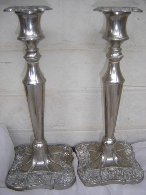 A pair of electoplated and decorated candlesticks for auction.