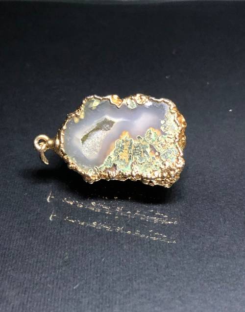A BESPOKE GREY AGATE PENDANT WITH GOLD GILDED EDGING