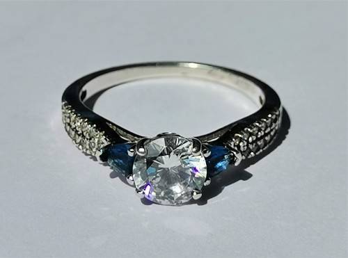 BEAUTIFUL SILVER RING WITH CLEAR MAIN STONE AND TWO BLUE STONES. WEIGHT: 2.5 GRAMS.