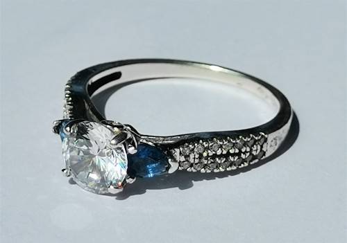 BEAUTIFUL SILVER RING WITH CLEAR MAIN STONE AND TWO BLUE STONES. WEIGHT: 2.5 GRAMS.