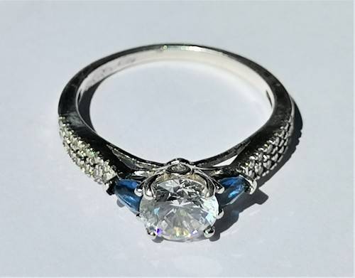 BEAUTIFUL SILVER RING WITH CLEAR MAIN STONE AND TWO BLUE STONES. WEIGHT: 2.5 GRAMS.