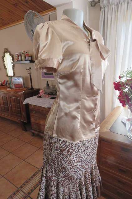 Dark cream shiny button down top with tie collar. Stretch polyester size 32/8. Puffed short sleeves.