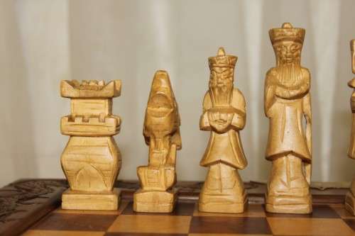 A SUPERB VINTAGE HAND-CARVED ORIENTAL FOLDING CHESS BOARD AND CARVED CHESS SET IN AWESOME CONDITION