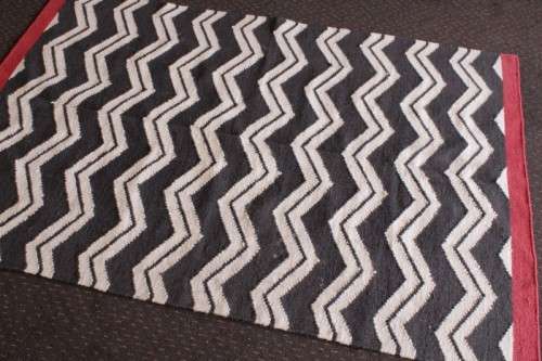 A beautifully made black and white "flat-weave" wool carpet with red edges in stunning condition