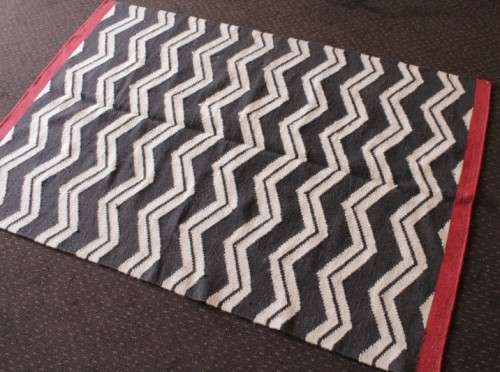 A beautifully made black and white "flat-weave" wool carpet with red edges in stunning condition
