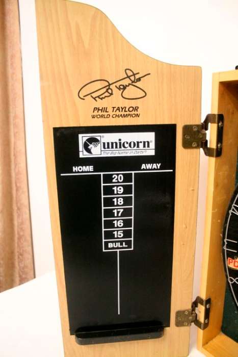 A top quality Unicorn (Phil Taylor)dart board in a wooden cabinet w score boards in super condition.