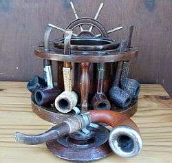 A collection of 7 quality pipes with wooden ship wheel pipe holder - includes Meerschaum