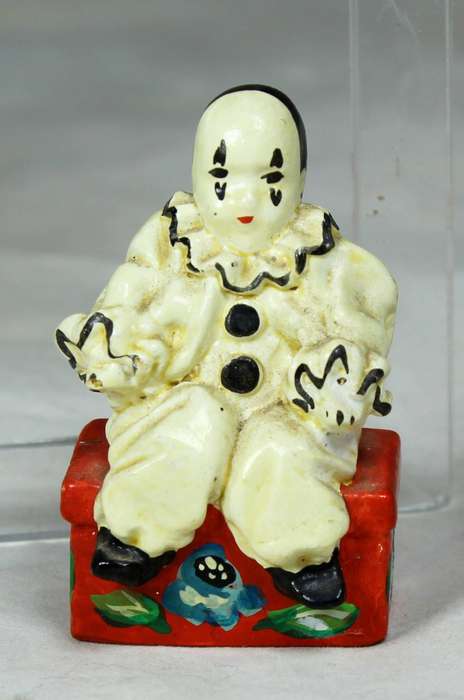 Miniature clown sitting on a chest