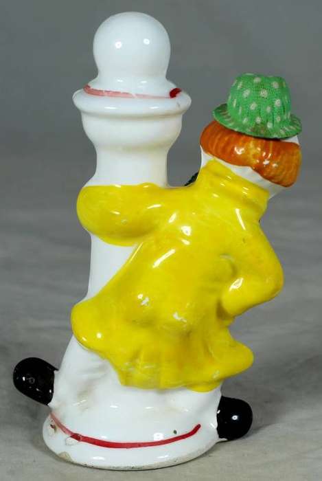 Porcelain clown in a green hat holding a lamppost