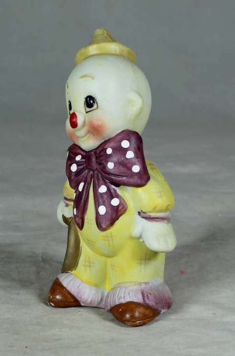 Ceramic clown in a brown bowtie carrying a ring