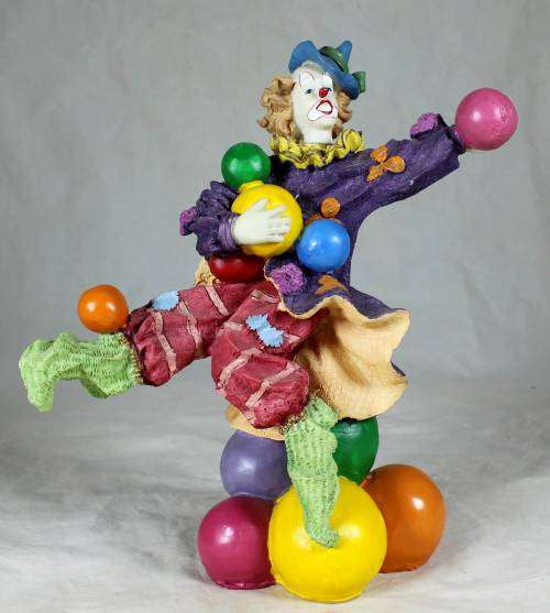 Clown standing on balls while juggling balls