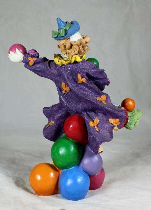 Clown standing on balls while juggling balls