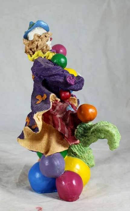 Clown standing on balls while juggling balls