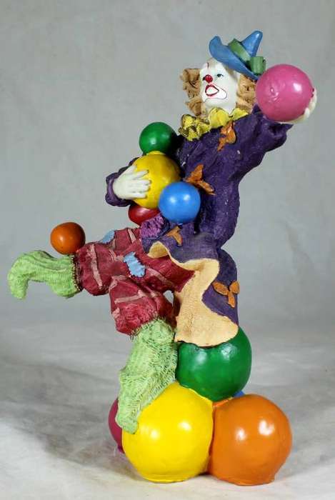 Clown standing on balls while juggling balls