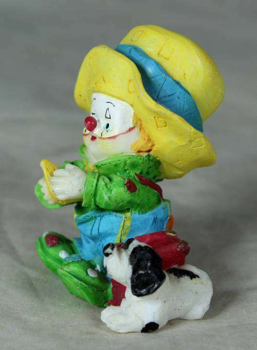 Molded clown in a large yellow hat with his dog
