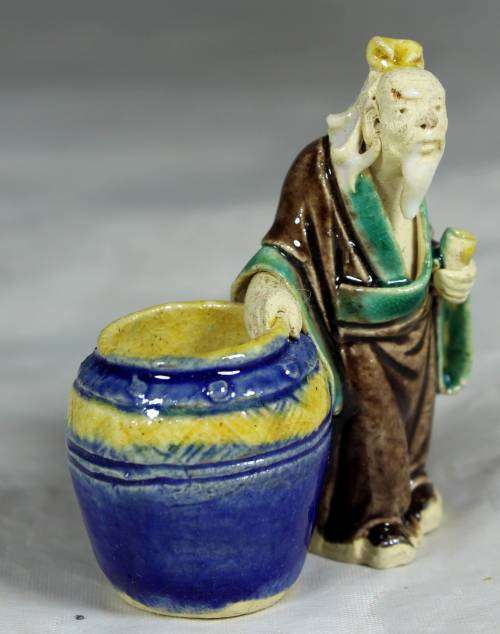 Mud men - old man holding onto a large barrel