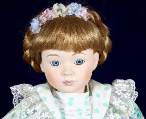 Porcelain doll girl in floral green dress on stand