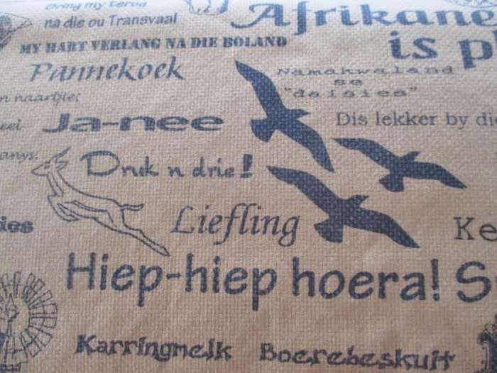 A very large, very long, wide table runner with South African scenes, songs and sayings