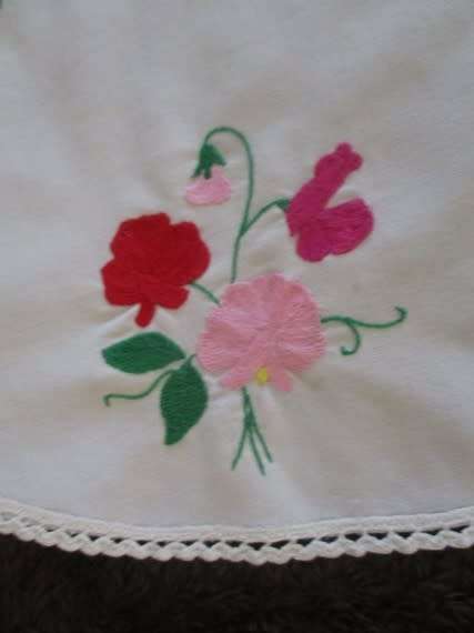 A larger round vintage neatly hand embroidered with sweet peas and hand crocheted border
