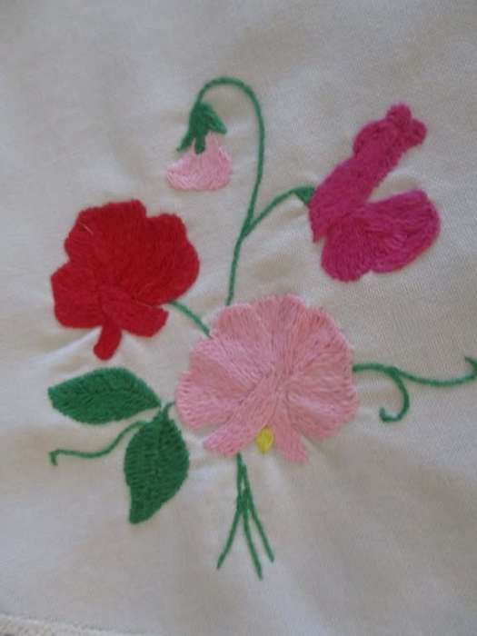 A larger round vintage neatly hand embroidered with sweet peas and hand crocheted border