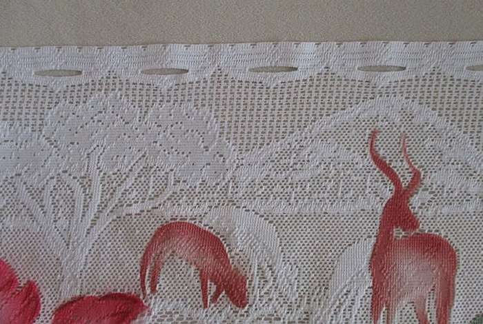 An unusual `half mast` lace curtain with with coloured proteas and animals