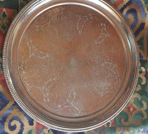 A VINTAGE ROUND SILVER PLATED SERVING TRAY SOLD AS IS
