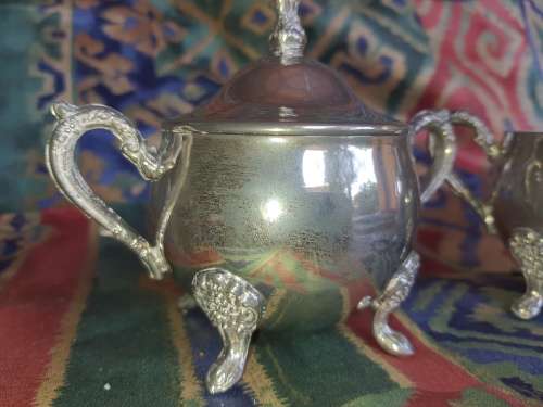 A VINTAGE PAIR OF SILVERPLATED UTENSILS , A CREAMER AND A SUGAR BOWL