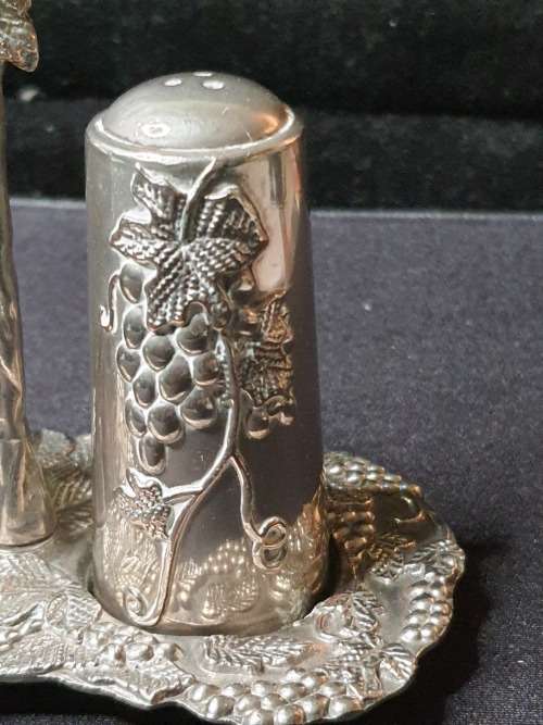 AN ORNATE SILVER PLATED SALT AND PEPPER STAND AND TWO SHAKERS SOLD AS IS