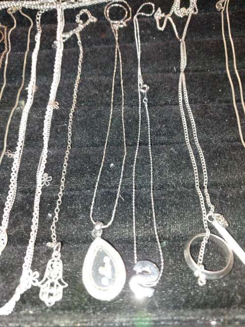 A COLLECTION OF SILVER PLATED AND STAINLESS STEEL NECKLACES WITH PENDANTS SOLD AS IS