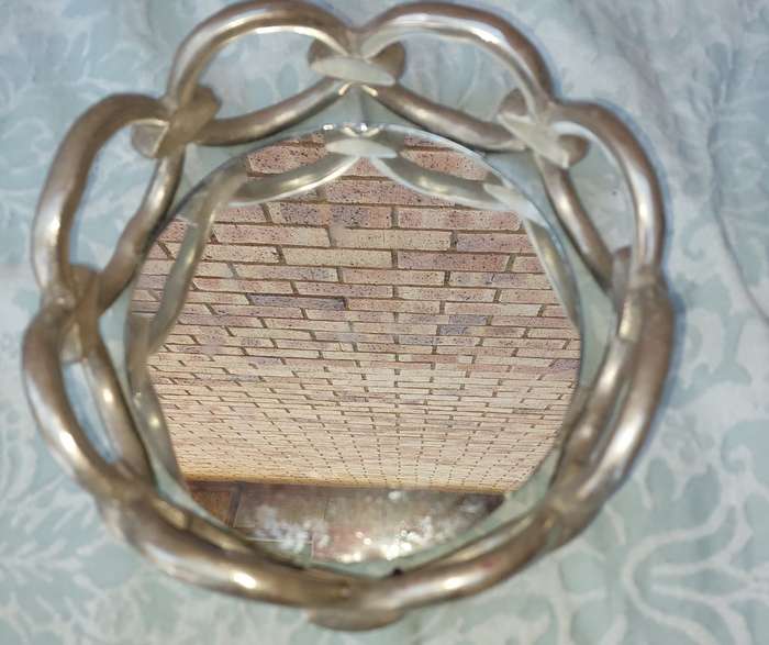 A ROUND CHAIN LINK STYLE ART DECOR SERVING TARY WITH A MIRROR BASE,