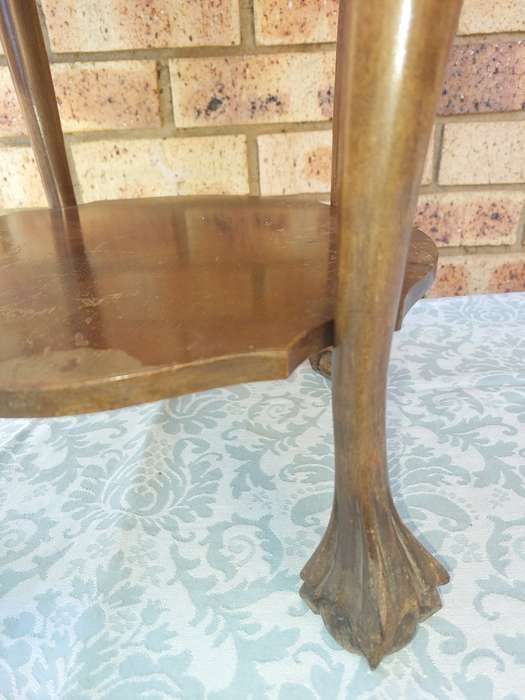 AN ANTIQUE SOLID WOOD TWO TEAR TEA TABLE WITH BALL N CLAW LEGS