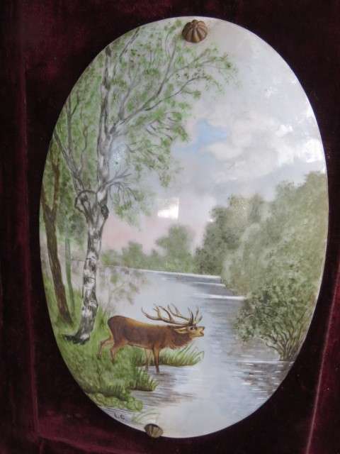 Pair of hand painted and signed porcelain oval plaques, mounted on felt frames