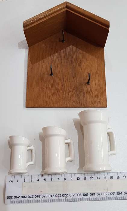 Vintage Dutch ceramic milk cans on hooks.