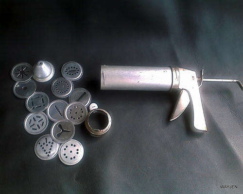 STEEL COOKIE CUTTER GUN WITH 13 INTERCHANGEABLE ATTACHMENTS.