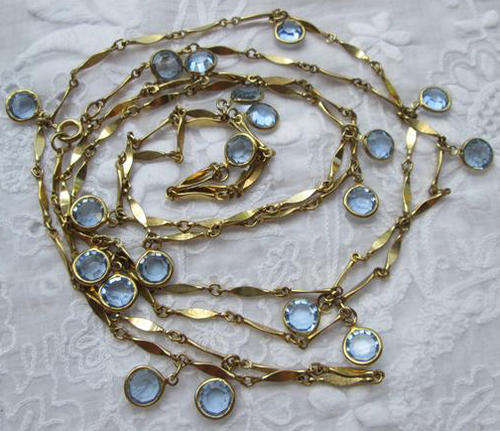 VERY LONG, GOLD TONE CHAIN NECKLACE SET WITH PRETTY SOFT BLUE GLASS STONES.