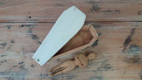 A wooden carving of a man in a box, shaped like a coffin, 25cm 9cm x 6cm